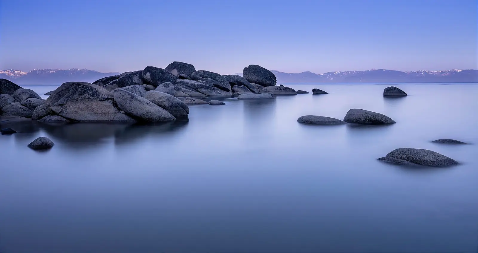 Deep blue Lake Tahoe below snowy mountains